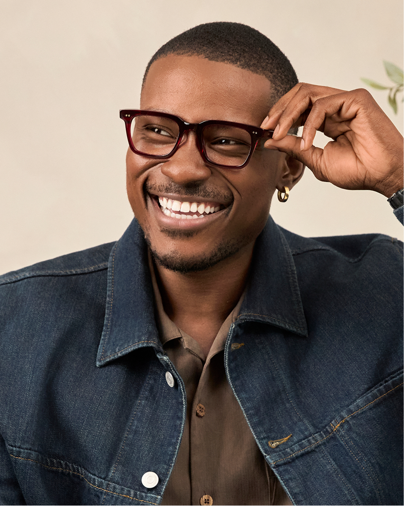 Smiling man adjusting dark rectangular Delancey Street glasses