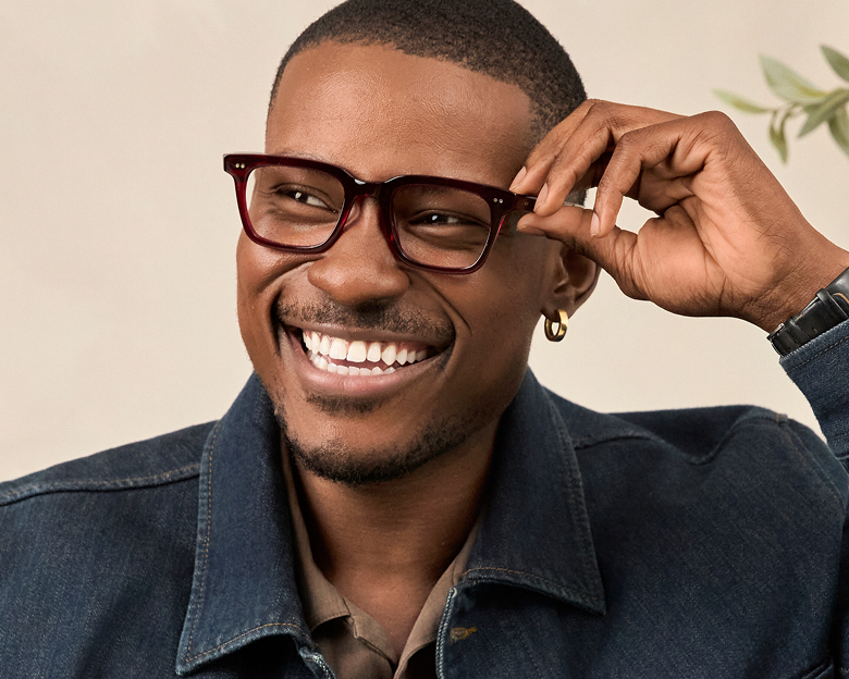 Smiling man adjusting dark rectangular Delancey Street glasses