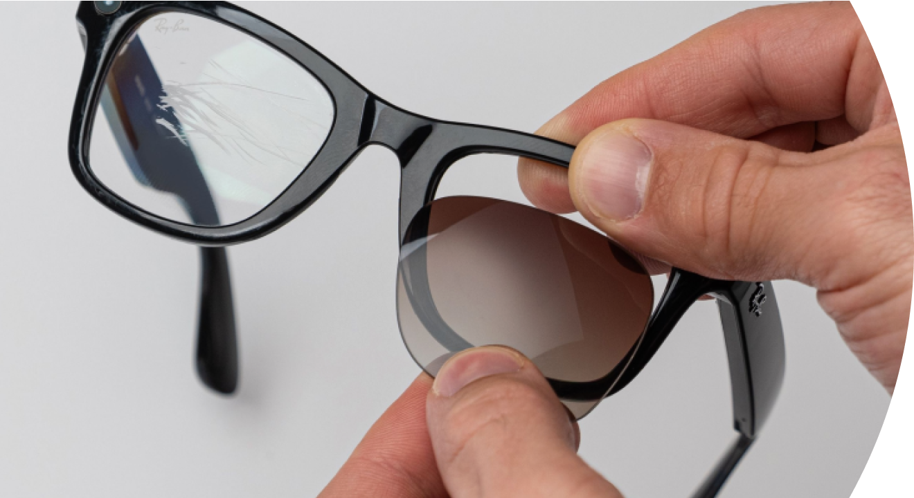 Hands fitting a replacement lens into a pair of black sunglasses