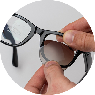Hands fitting a replacement lens into a pair of black sunglasses