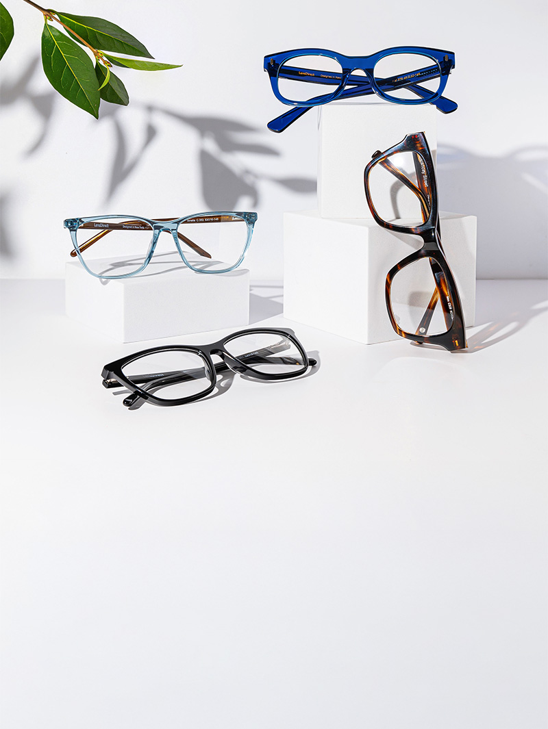Glasses frames displayed on a white background with a plant behind it